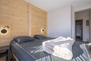 A bedroom with a bed and two lights on the wall