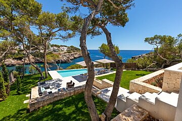 A swimming pool surrounded by trees with a view of the ocean