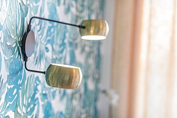A wall with a patterned wallpaper and two lights on it