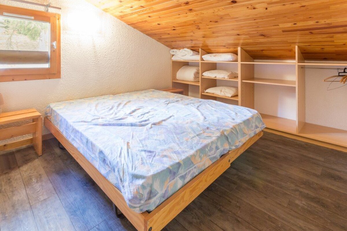 A bedroom with a bed and shelves with pillows on them
