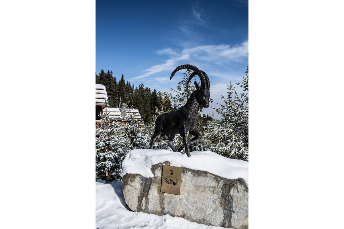 A statue of a goat standing on top of a snow covered rock