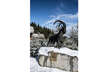 A statue of a goat standing on top of a snow covered rock