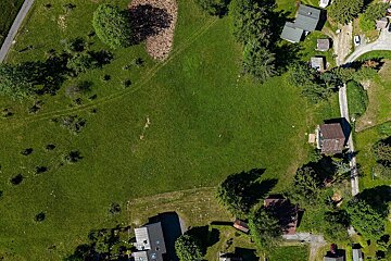 Aerial view of a large green field surrounded by houses and trees.