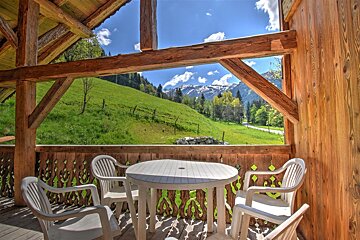 A table and chairs on a balcony overlooking a mountain range