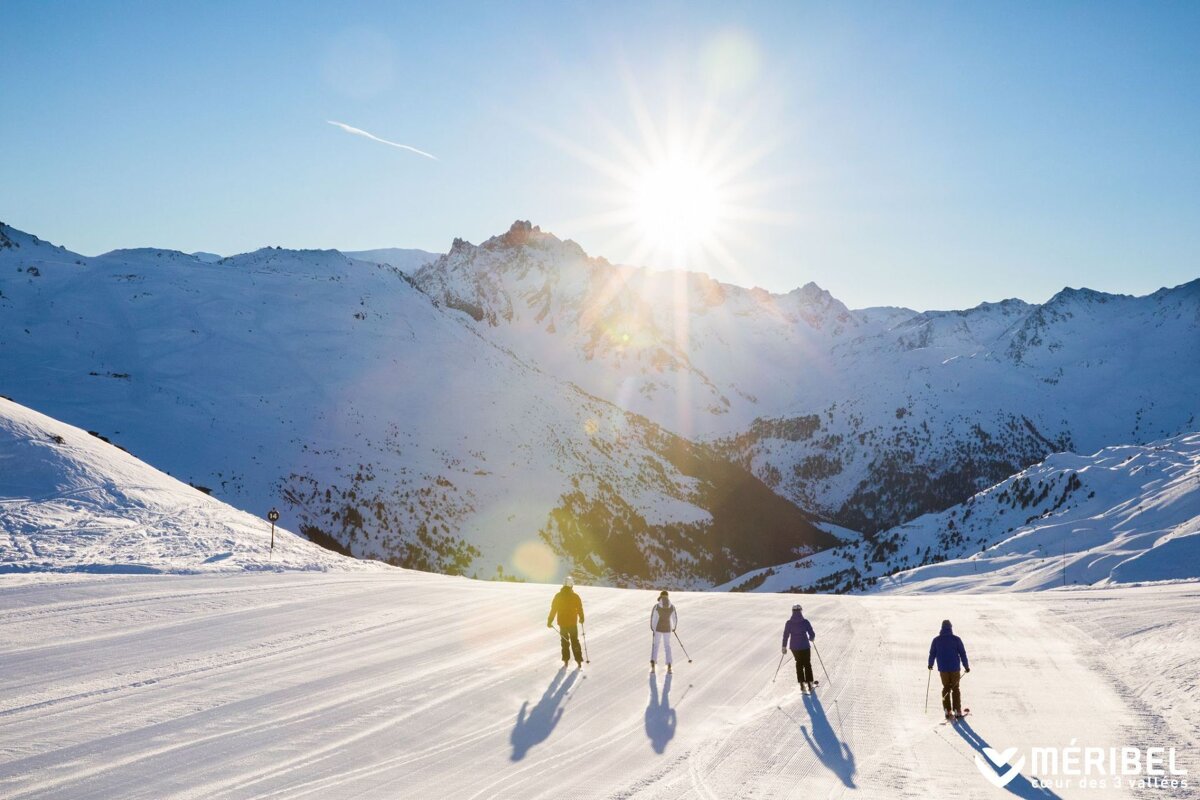 A group of people skiing down a snow covered slope in the mountains