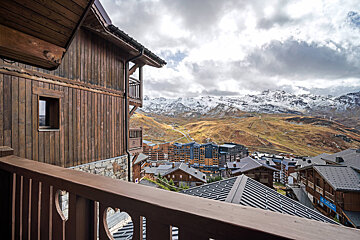 A balcony overlooking a ski resort with mountains in the background