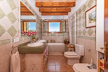 A bathroom with two sinks a toilet and a window