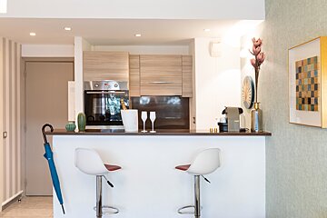 A kitchen with two bar stools and a nespresso machine
