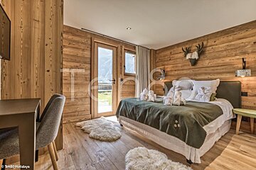 A bedroom with a wooden wall and a bed with a green blanket