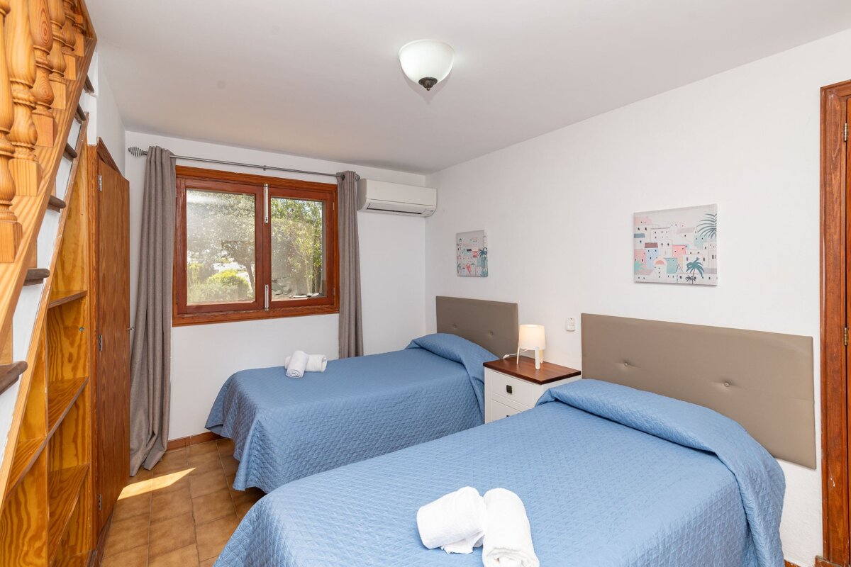 A bedroom with two beds and two paintings on the wall