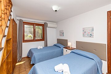 A bedroom with two beds and two paintings on the wall