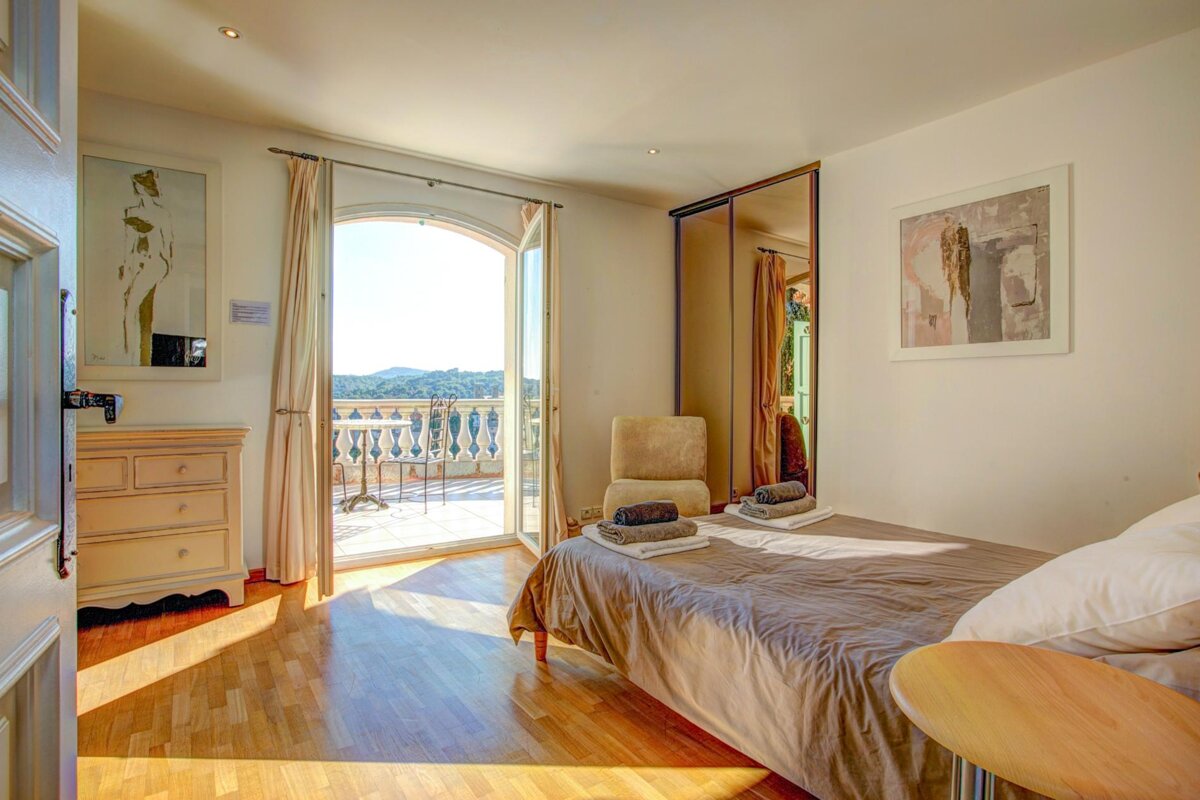 A bedroom with a single bed and a balcony