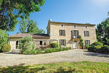 A large stone house with green shutters on the windows
