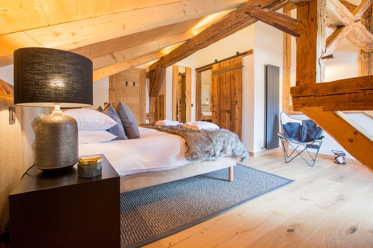 A bedroom with a bed and a lamp on the nightstand