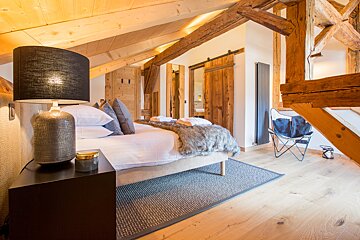 A bedroom with a bed and a lamp on the nightstand