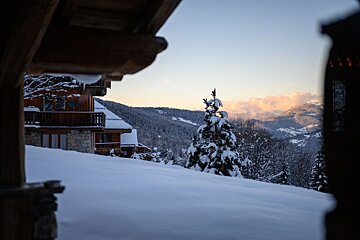 A snowy landscape with a house in the background