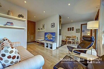A living room with a couch a chair and a television from mountain base immobilier real estate