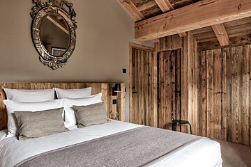 A bedroom with a bed and a mirror above it