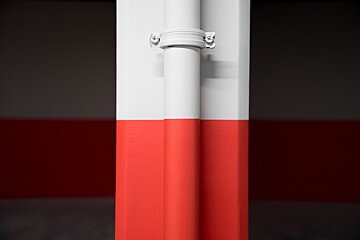 A white pipe is attached to a red and white wall
