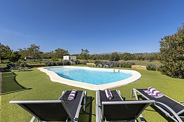 A swimming pool is surrounded by lawn chairs and towels