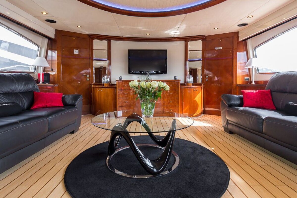 A living room with a black couch and a glass table