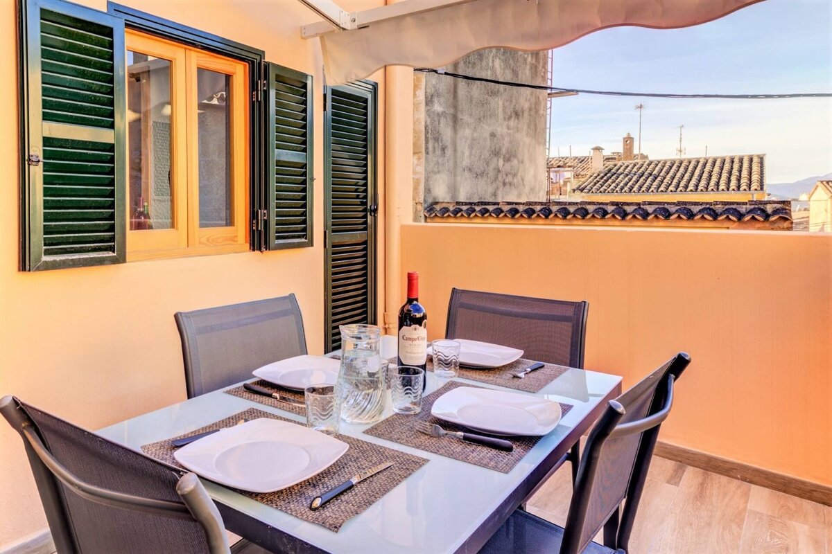 A bottle of wine sits on a table with plates and utensils