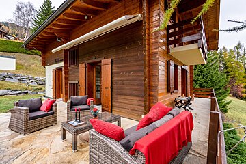 A wooden house with a couch and chairs in front of it