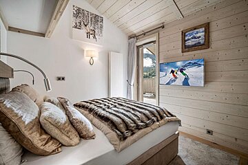A bedroom with a bed and a flat screen tv on the wall