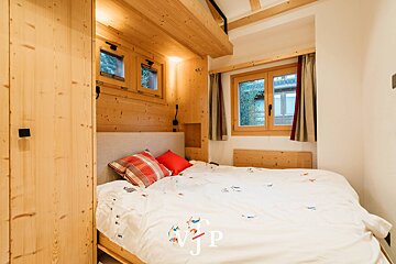 A bedroom with a bed and a window with the letters jp on the bottom