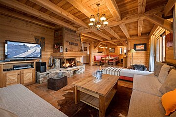 A living room in a wooden cabin with a fireplace and a tv