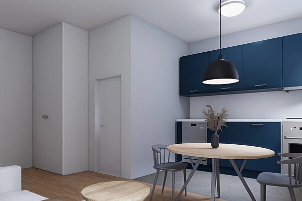 A modern kitchen and dining area with deep blue cabinets, a light wood round table, gray chairs, and minimalist white walls with a door.