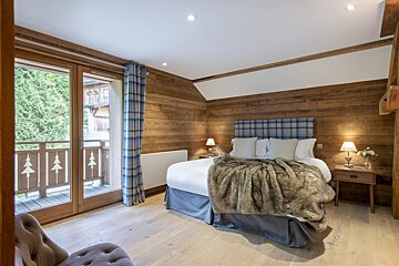 A bedroom with wood paneling and a bed with a plaid headboard
