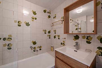 A bathroom with green and yellow leaves on the tiles
