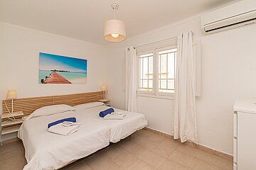 A bedroom with two beds and a painting on the wall