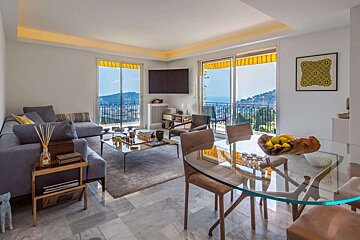 Modern living/dining room with a luxurious sea view balcony, stylish furnishings, marble floor, and sunny yellow awnings.