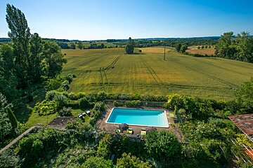 An aerial view of a swimming pool surrounded by lush greenery