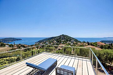 A balcony with a view of the ocean and mountains