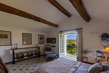 A bedroom with a bed a chair and a television