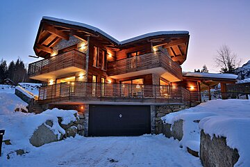 A snow covered driveway leading to a large house