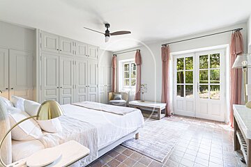 A bedroom with a large bed and a ceiling fan