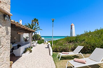 Two lounge chairs in front of a house with a view of the ocean