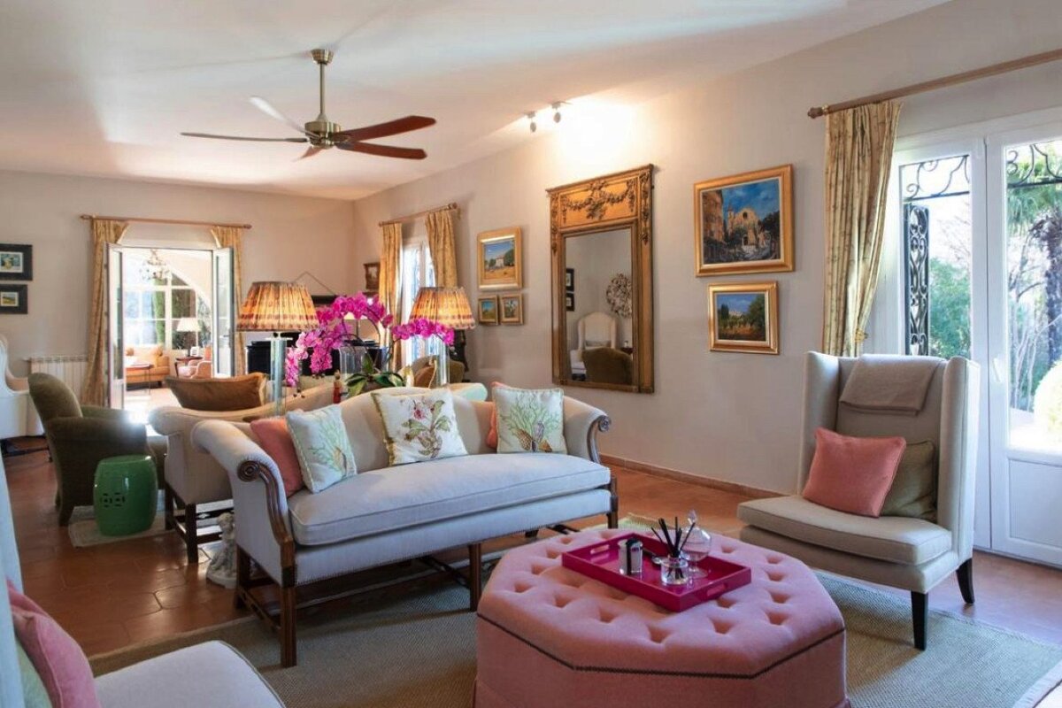 A living room with a white couch and pink ottoman