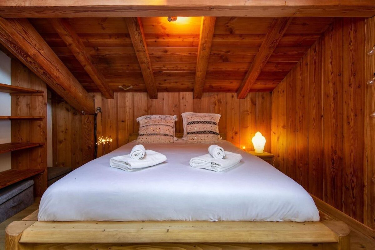 A bed with white sheets and pillows in a wooden room