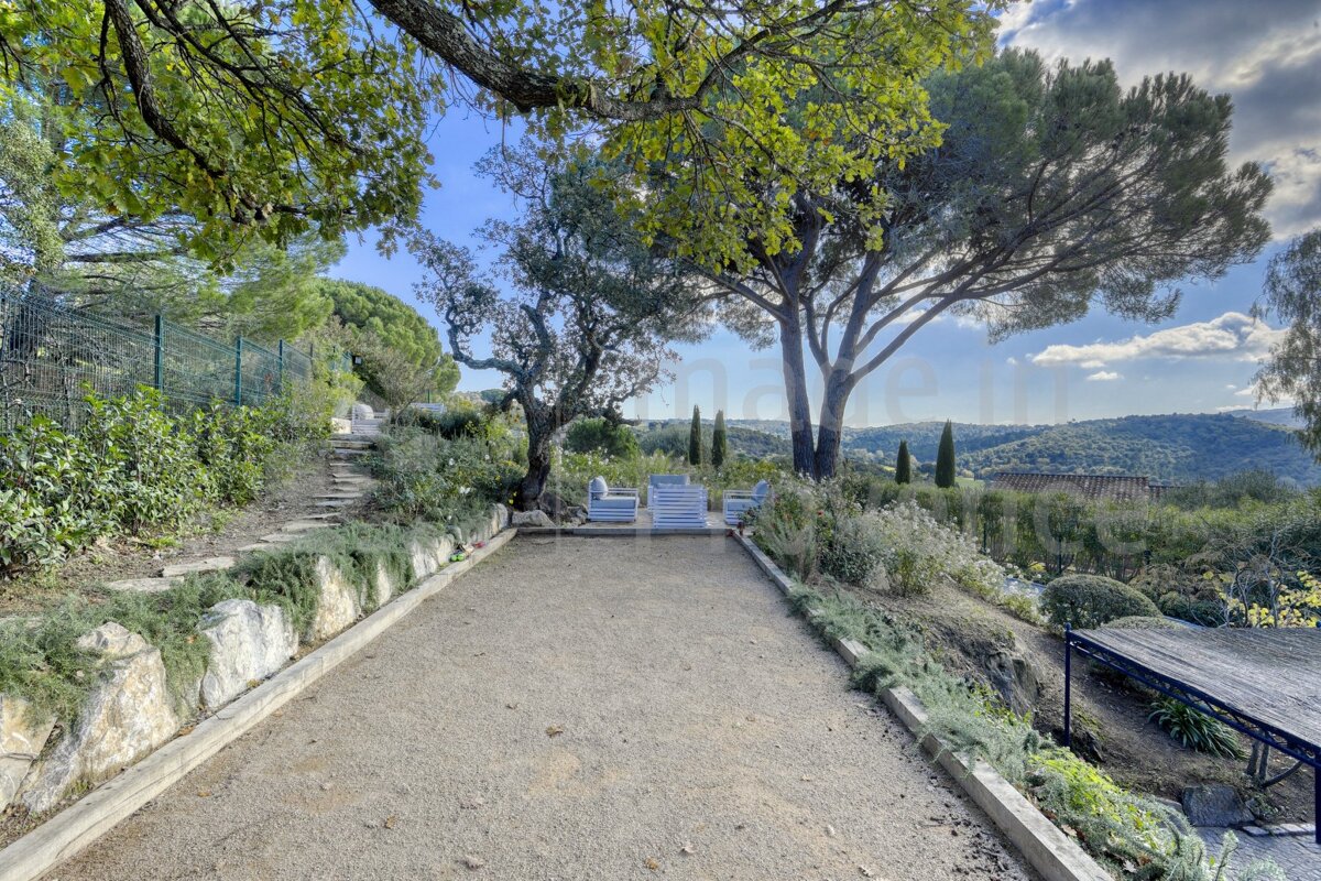 A fenced in area with a table and chairs surrounded by trees