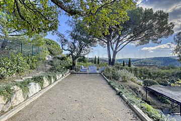 A fenced in area with a table and chairs surrounded by trees