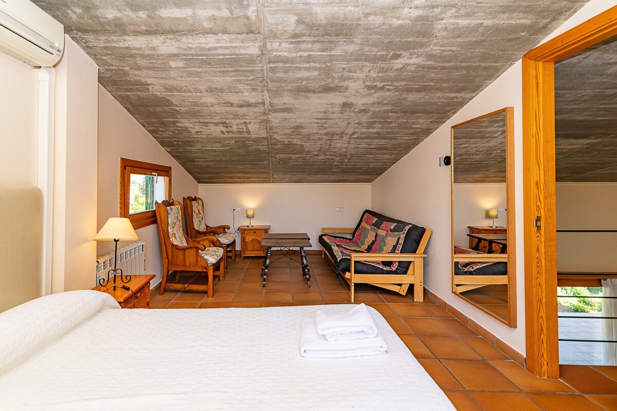 A bedroom with a couch and a mirror on the wall