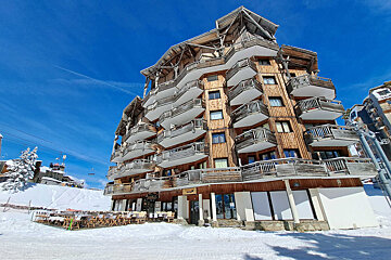 A building with a lot of balconies is covered in snow