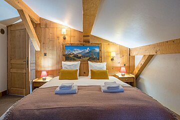 A bedroom with a painting on the wall above the bed