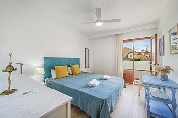 A bedroom with a blue bed and a ceiling fan
