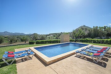 A large swimming pool with blue lounge chairs around it